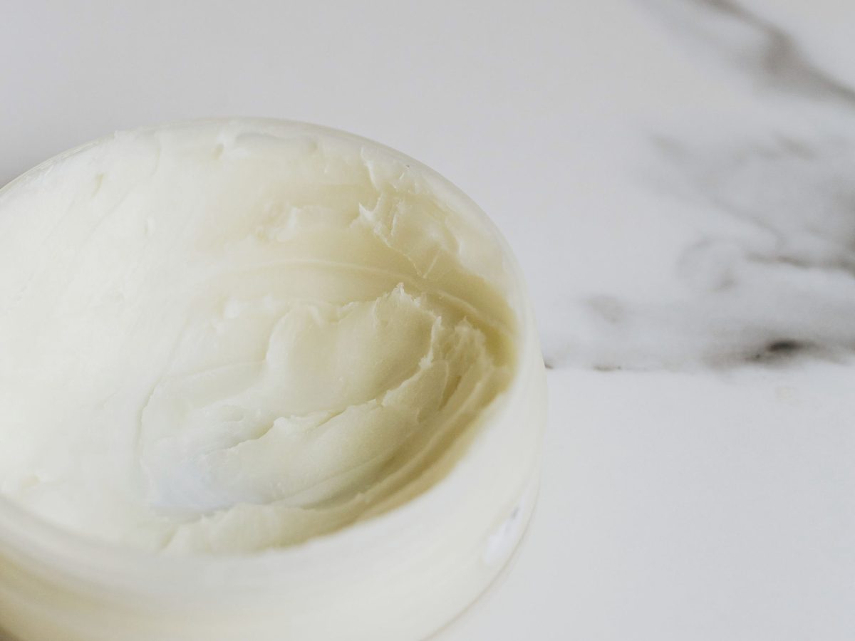 A cosmetic cream in an open jar on marble