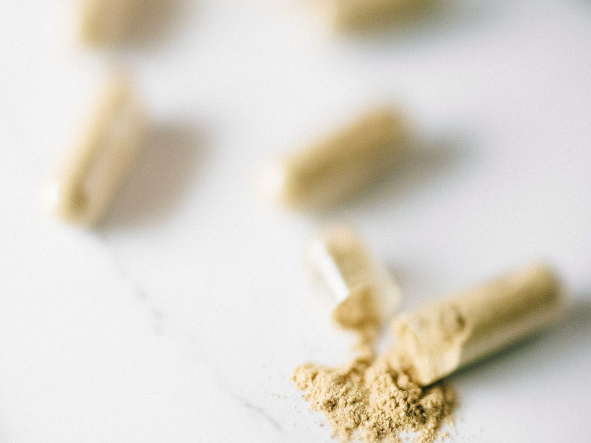 Open capsules with botanical extract powder on a marble surface