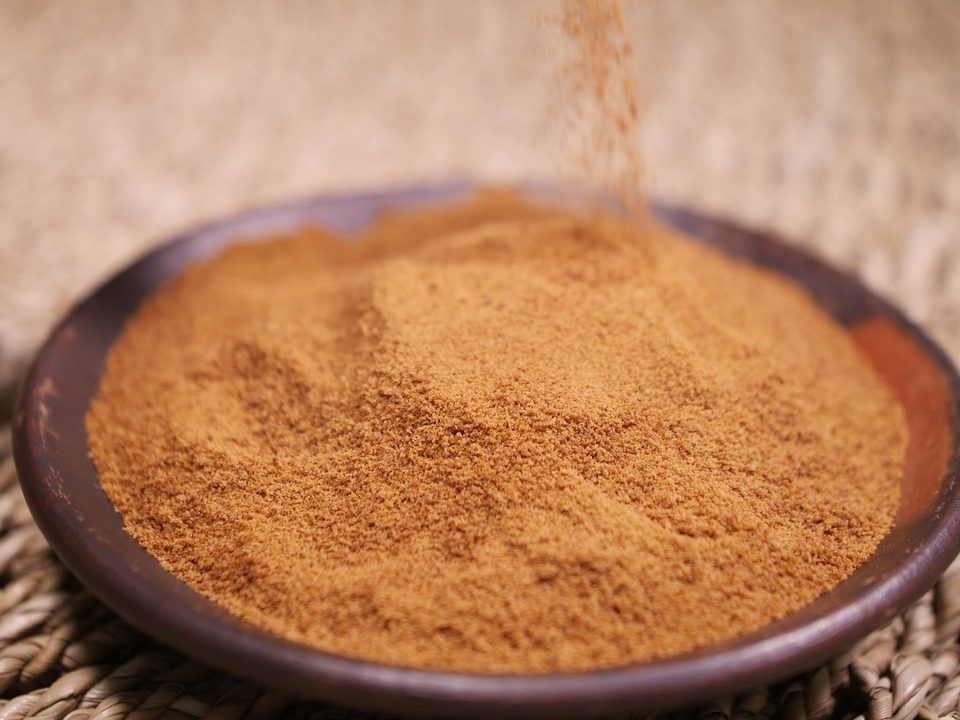 Shatavari extract, a yellowish-brown powder poured from a wooden spoon into a dish