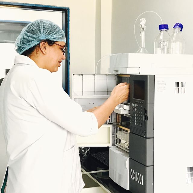An analyst loading samples into a chromatograph in a quality control laboratory